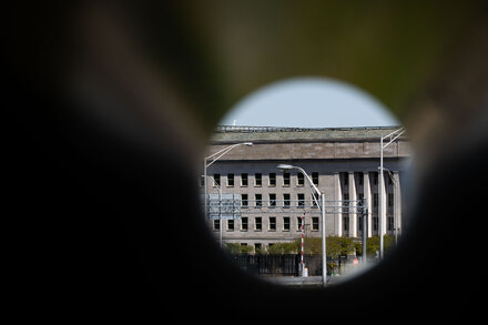 A close-up shot of the Pentagon building with a dramatic sky overhead, emphasizing its imposing and secretive nature. The lighting suggests a serious or urgent tone.