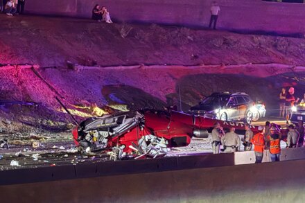 Rescue workers attend to an injured person next to the wreckage of a helicopter on a highway in Sacramento after a crash.
