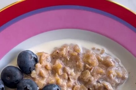 A bowl of Sticky Date and Brown Butter Oatmeal topped with chopped dates and a drizzle of brown butter, with a spoon resting in it.