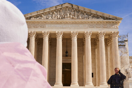 A gavel rests on a stack of law books, with the Supreme Court building visible in the background, symbolizing a legal decision on transgender care.