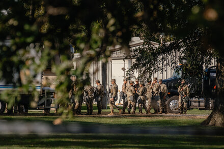 Texas National Guard troops in formation, possibly during an arrival or deployment, with military vehicles in the background.