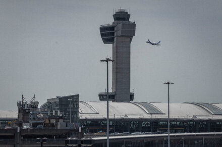An airplane taking off with a blurred background of an airport and city skyline, illustrating the potential impact of a government shutdown on air travel.