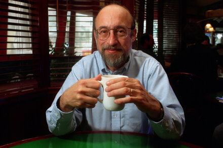 Thomas Perry, an older man with short gray hair and glasses, looks directly at the camera with a gentle smile.