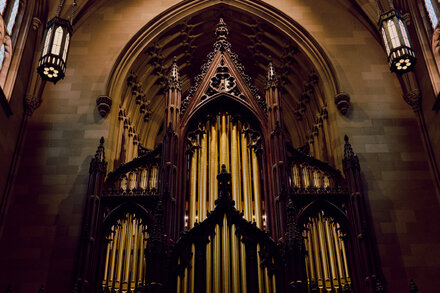 A close-up shot of the intricate pipes and wooden casework of the new organ inside Trinity Church, with soft light illuminating its details.
