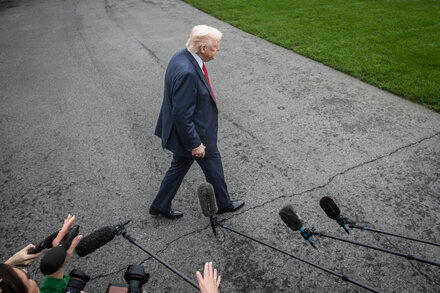 Donald Trump with a serious expression, gesturing while speaking at a podium.