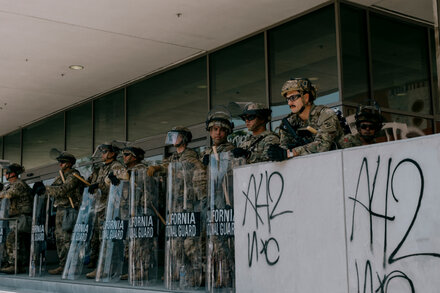 California National Guard troops stand in formation during a training exercise. The troops are wearing camouflage uniforms and carrying rifles.