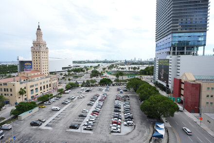 Rendered image showing a modern, multi-story building with 'Trump Presidential Library' inscribed, surrounded by palm trees and a waterfront view in Miami.