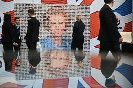 A group of people, possibly Conservative Party members, gathered at a political event, perhaps looking pensive or engaged in discussion. The setting appears to be a conference hall or meeting room.