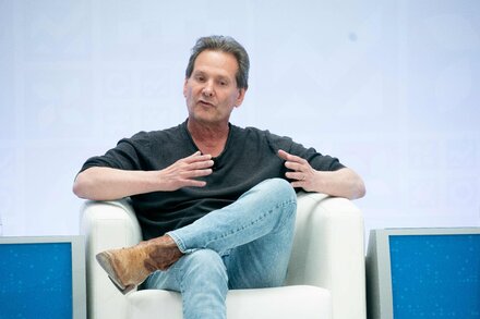 Verizon CEO Hans Vestberg and former PayPal CEO Dan Schulman shaking hands in a corporate office setting, with Verizon's logo subtly visible in the background.