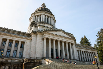 Debris scattered on the floor of the Washington State Capitol with a damaged statue and fire extinguisher foam visible after a man broke in and caused destruction.