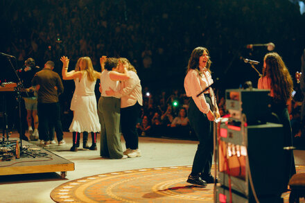 Singer-songwriter Lucy Dacus officiates a wedding ceremony onstage during a concert, with the marrying couple exchanging vows in front of a large audience.